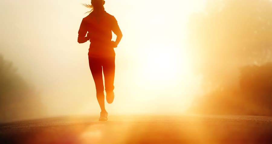 Runner athlete feet running on road. woman fitness silhouette sunrise jog workout wellness concept.